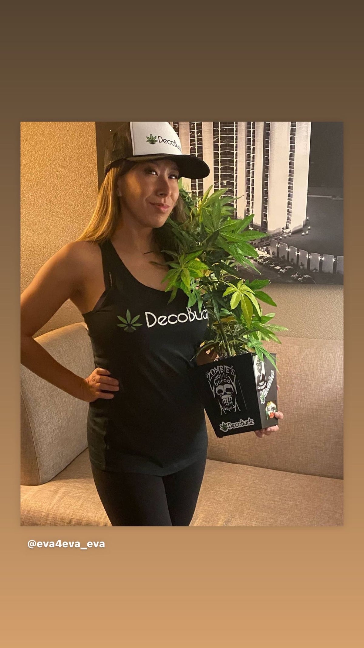 DecoBudz girl wearing a DecoBudz trucker hat, posing with a lifelike DecoBudz plant, combining cannabis-inspired fashion and decor