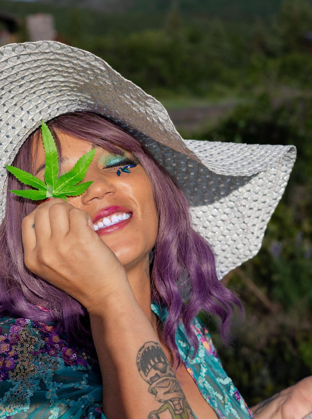 Artsy shoot of a girl holding a lifelike DecoBudz faux cannabis leaf over her eye, blending style and creativity with cannabis-inspired decor