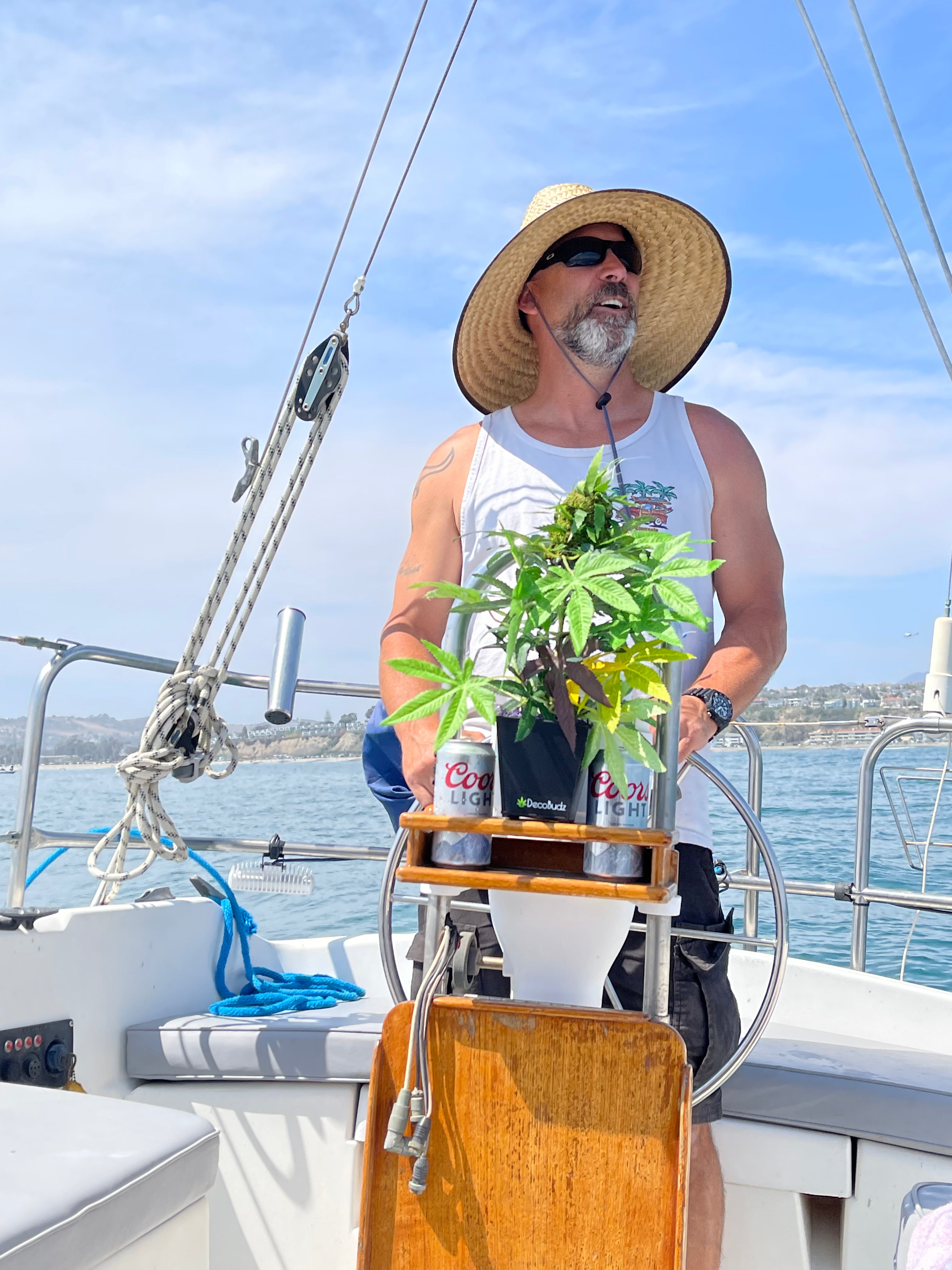 Faux weed plant by DecoBudz displayed on a sailboat with a salty captain, blending cannabis decor with an adventurous maritime scene.